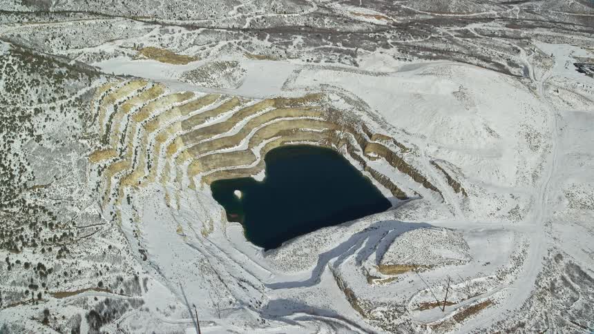 Aerial panorama of snowcovered mountains with a crater filled with water