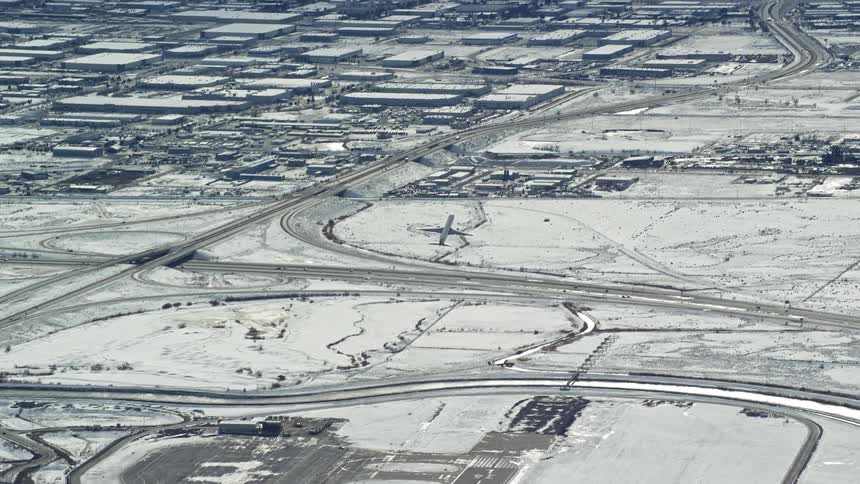 Airliner takes off over snow covered urban landscape during winter
