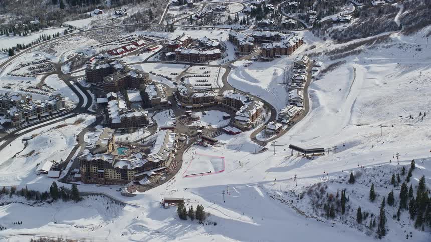 Aerial view of hotels in a residential area covered in snow next to mountains
