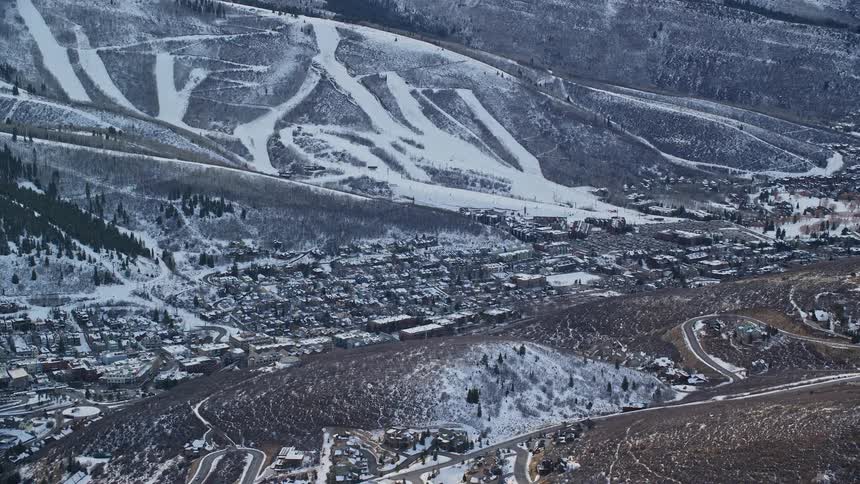 Aerial panorama of an urban city nestled among hills and next to snowcovered mountains
