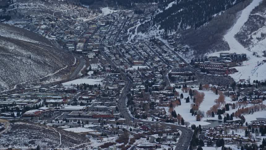 A city with many houses and close to mountains and the region is snowy