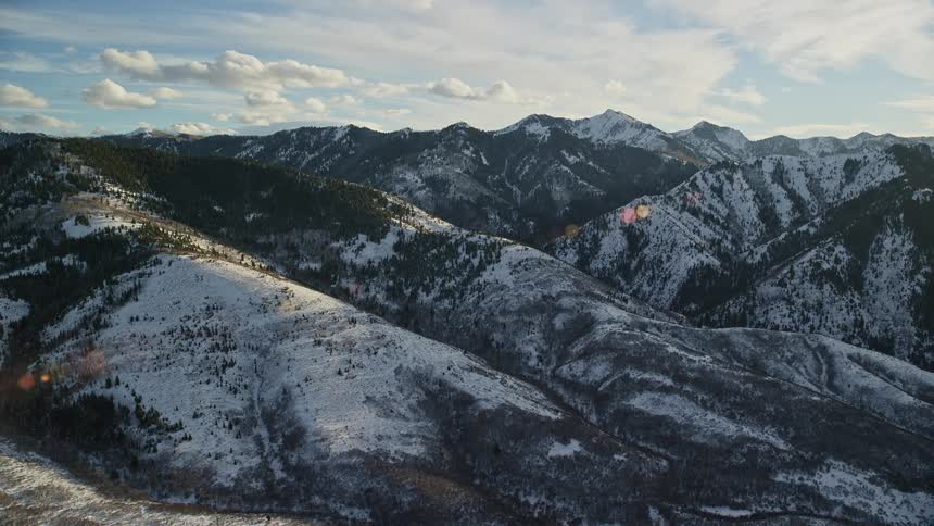 Aerial panorama of a mountain range covered in snow in the morning