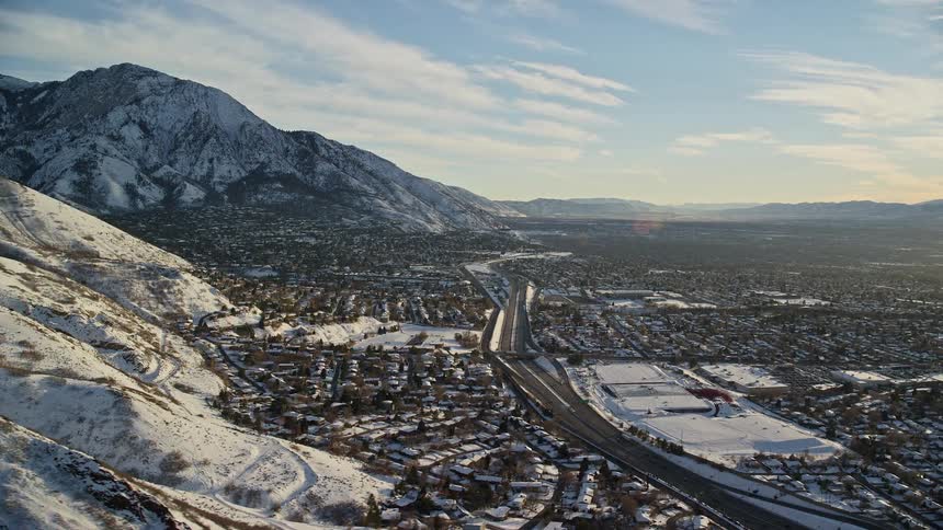 A large suburban city next to a mountain range all covered in snow