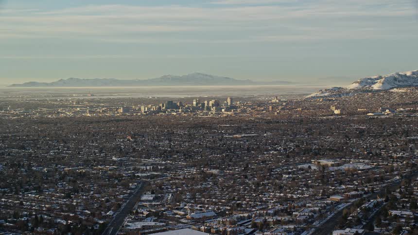 Aerial panorama of a snowcovered metropolis with a mountain range on the horizon on a morning