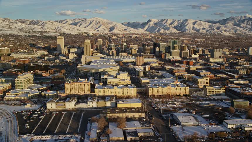 Aerial view of a large city with buildings houses and warehouses with snowcovered mountains in the background