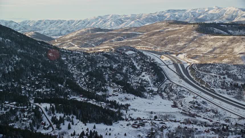 Aerial panorama of a road amidst a mountain range covered in snow
