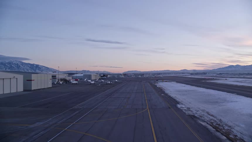 An aerial view of an airport runway with several planes on the left side parked