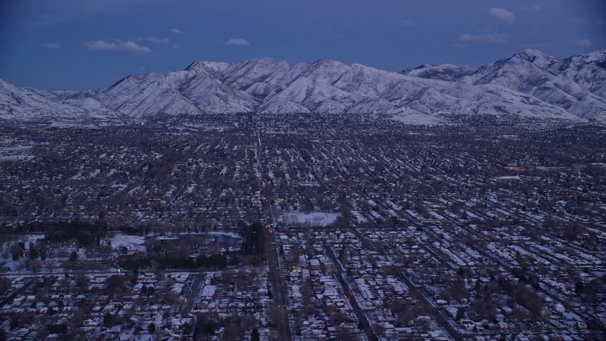 Aerial view of snowy cityscape with snowy mountains in the background