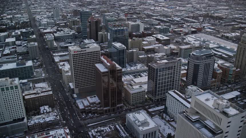 Aerial of downtown with snow on the roofs of neutral colored buildings early morning as the sun is just begining to rise