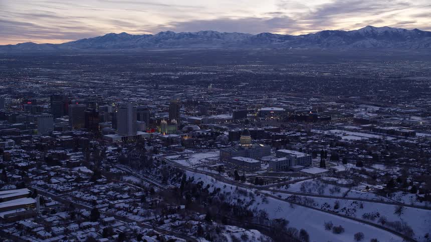 From above the state capitol and downtown salt lake city unfold in the soft twilight blanketed by winter snow creating a serene and captivating aerial view
