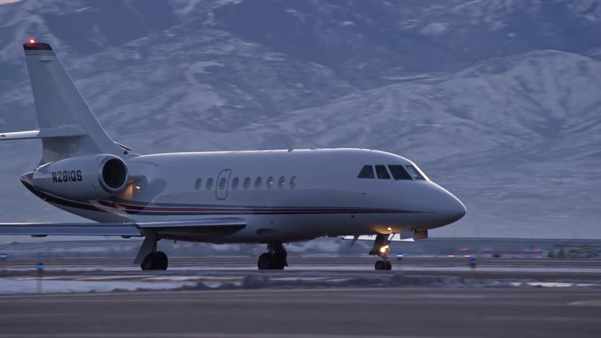 An airplane proceeding on the ground on a runway near snowy mountains