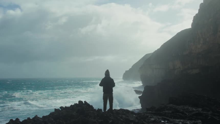 Photographer stands on coast and takes a picture on a cloudy day