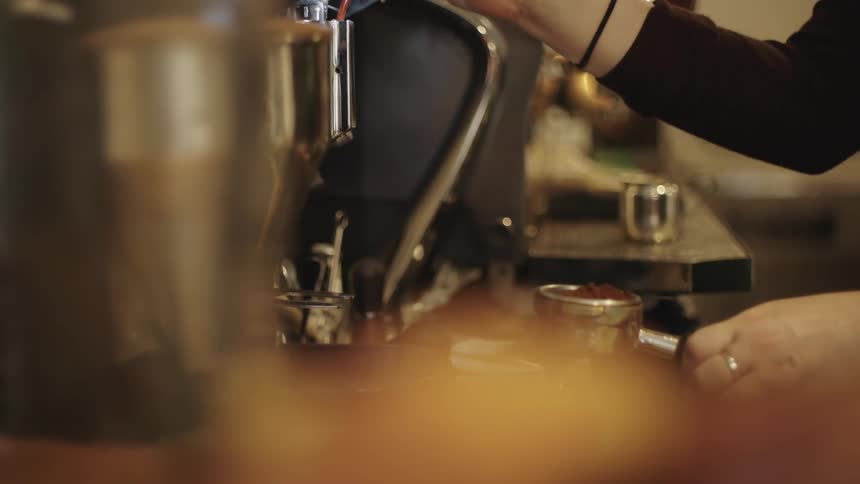 Closeup of hands preparing coffee from a machine