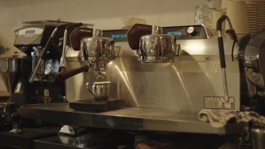 Someone is making coffee using a machine in a shop