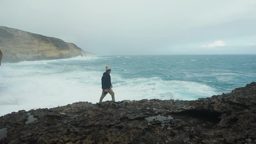 A man walks along the beach with a camera in his hand