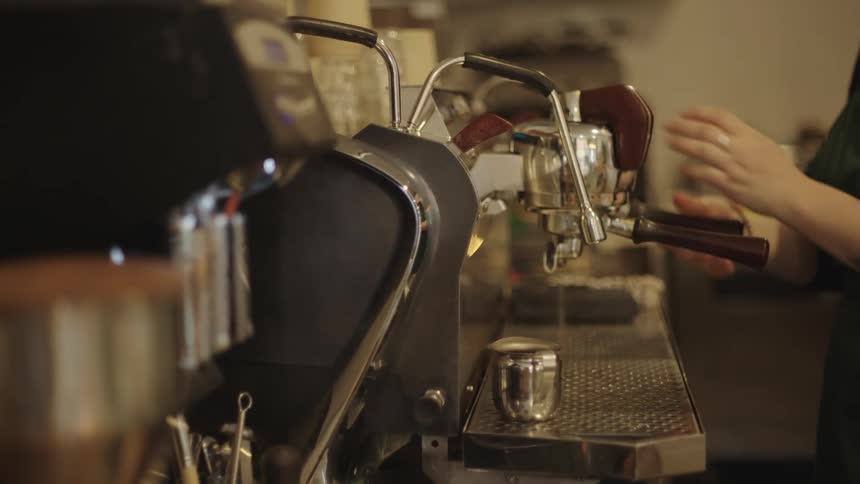 A person washing coffee machine in a busy cafe