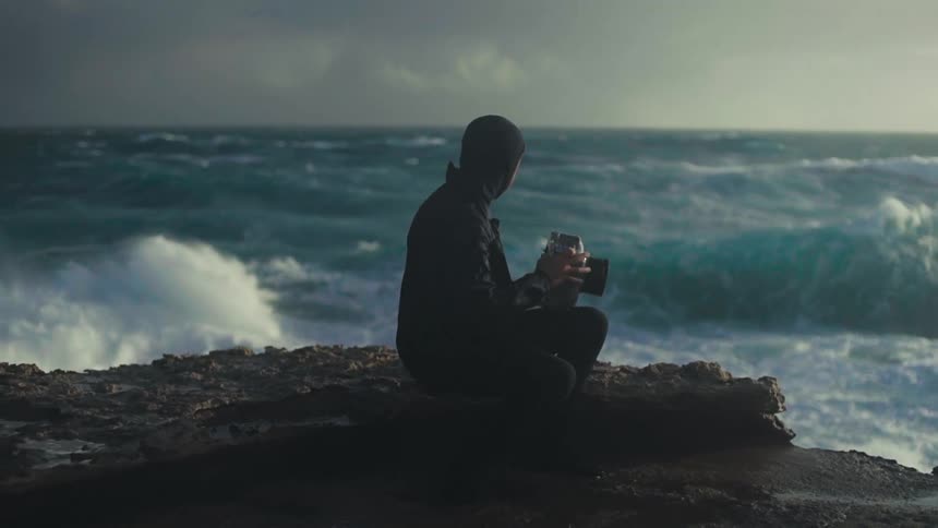 A man is taking pictures of the windy coast