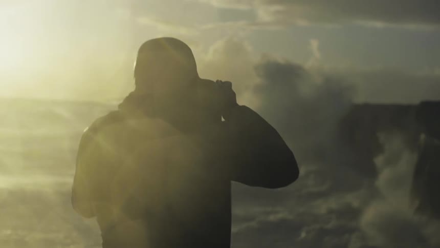 A cameraman is pointing the camera at waves crashing on the shore