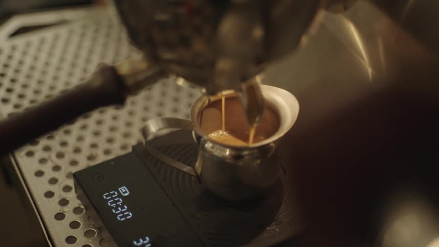 Closeup of a machine pouring cappuccino into a metal cup