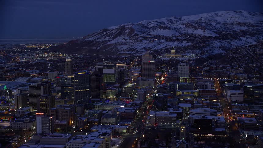 A city view at sundown during winter as a mountain with snow is seen beyond the city view
