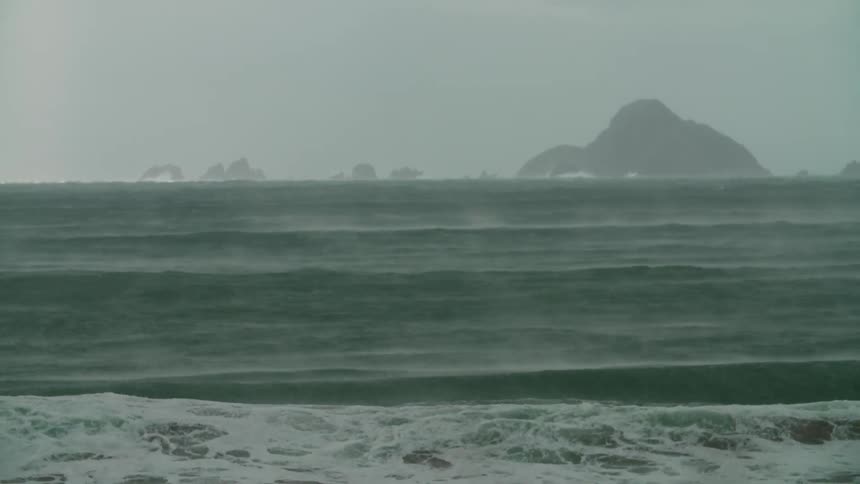A strong wind hitting sea waves making them break on the shore