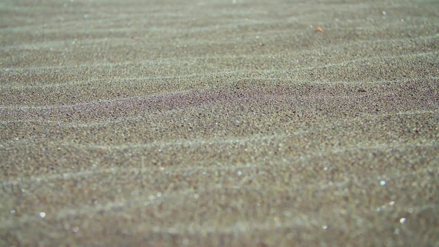 A floor with a sandy texture and some small shiny grains