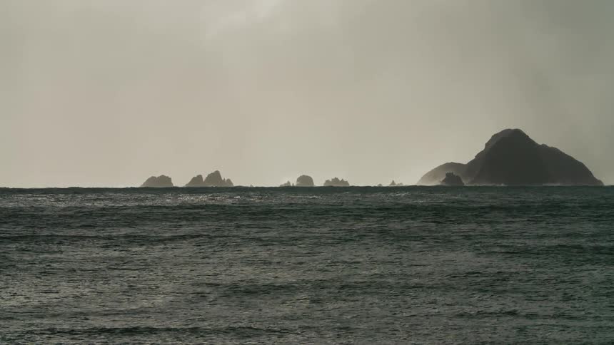 Mountains in the middle of the ocean with gentle waves at sunset