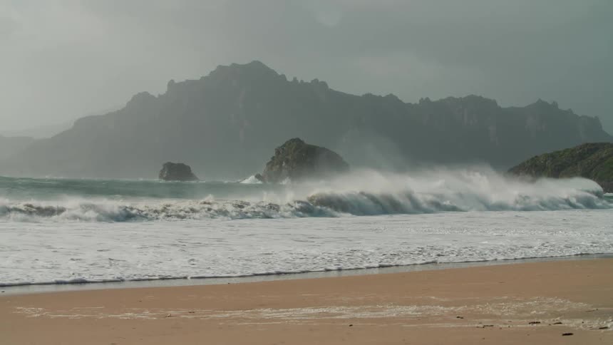 View of the beach with strong waves and the coastline