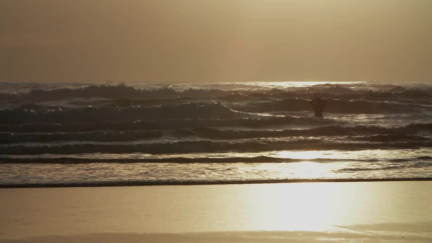 Person walking into the sea at the beach alone at dawn
