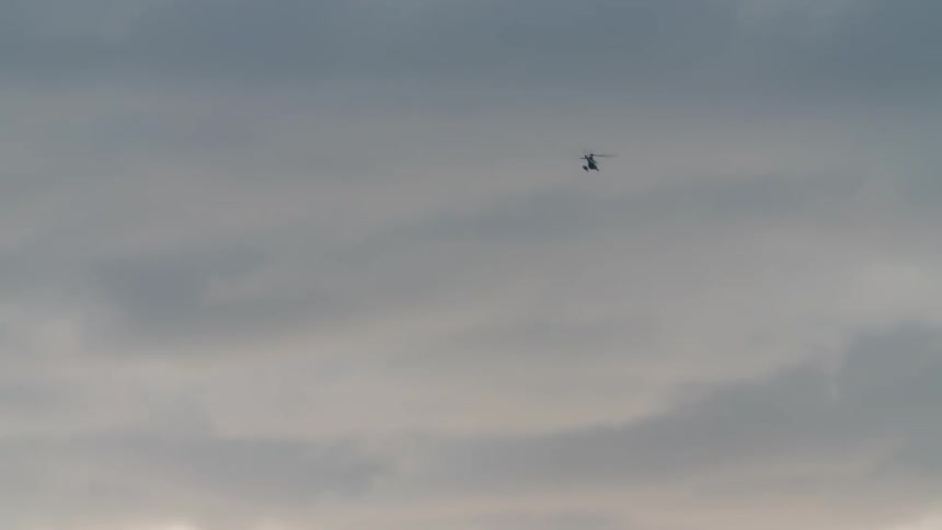 A helicopter flying in the cloudy sky during sunset