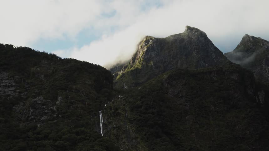 A mountain covered in vegetation and a small waterfall