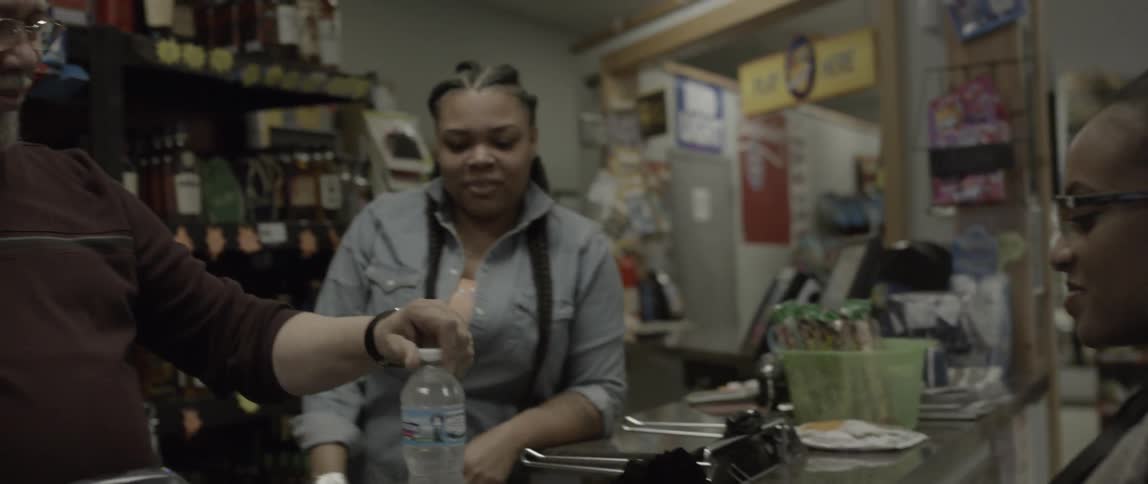 A woman goes to the counter of a store to buy water