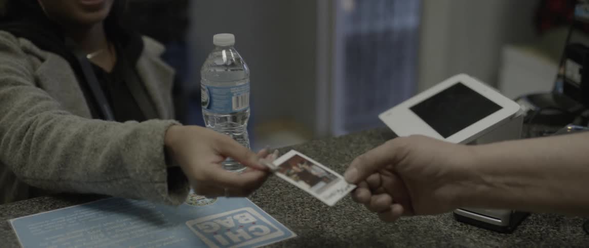 Woman sitting at a table hands an old polaroid to someone