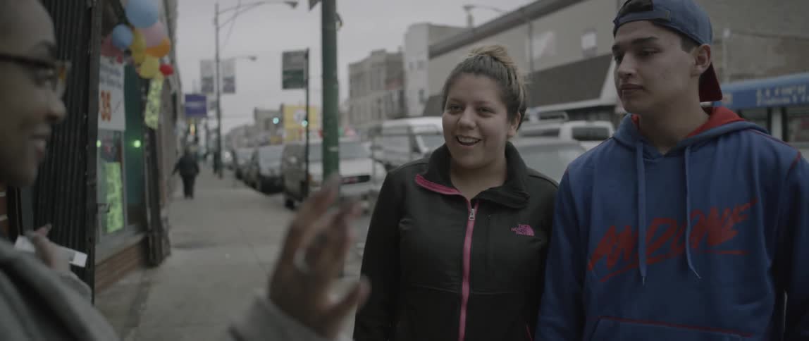 A woman stops a couple to take a photograph