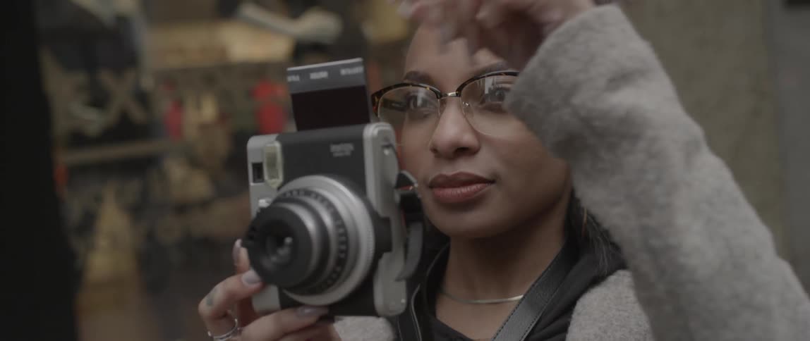 A photograph comes out of a camera after she takes a picture