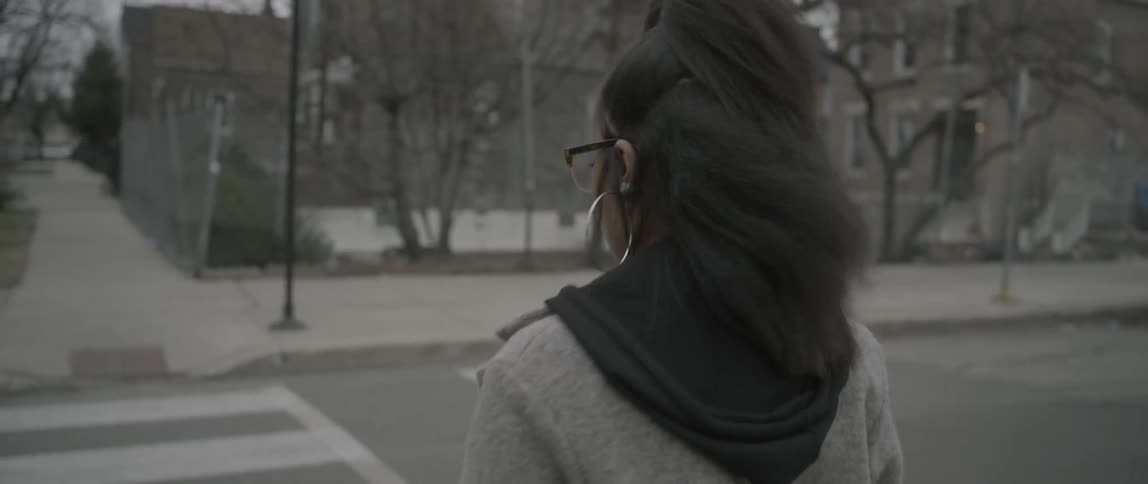 A woman is crossing the street on a windy day