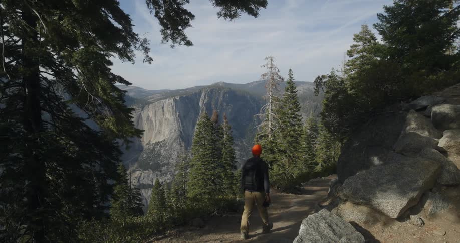 Man hiking in the mountains with his back turned during daylight