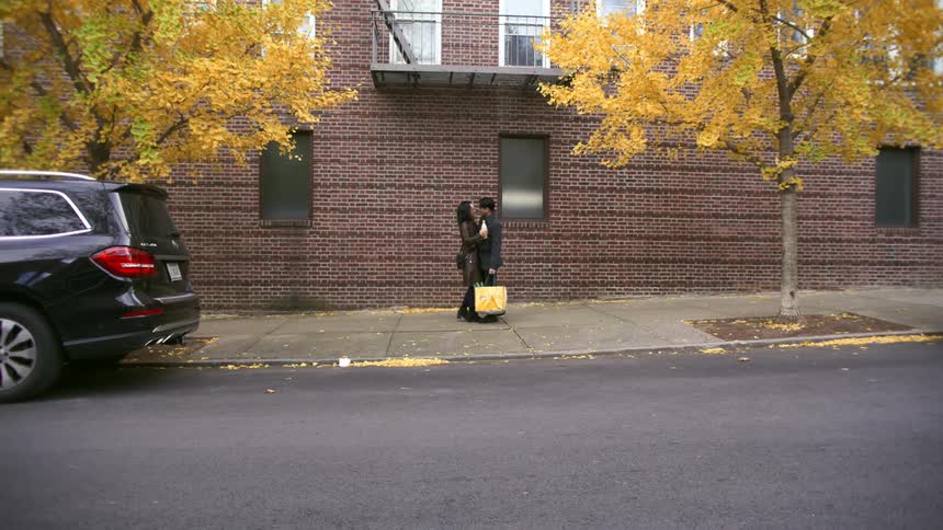 Two people meet on the sidewalk and hug