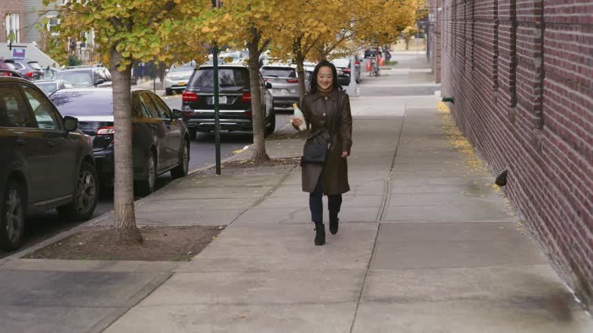 Woman walking on a sidewalk holding a white bottle
