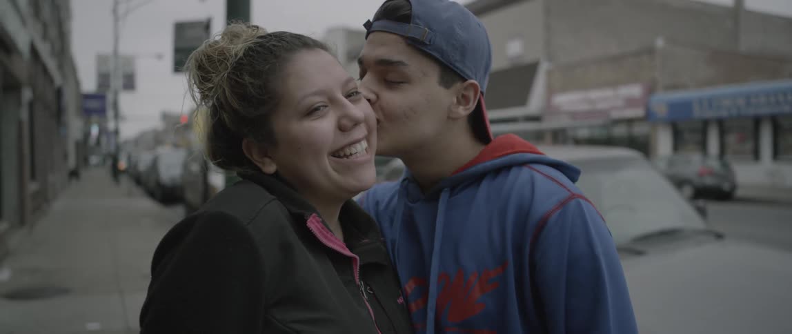 Man kisses a woman on the cheek on a city sidewalk
