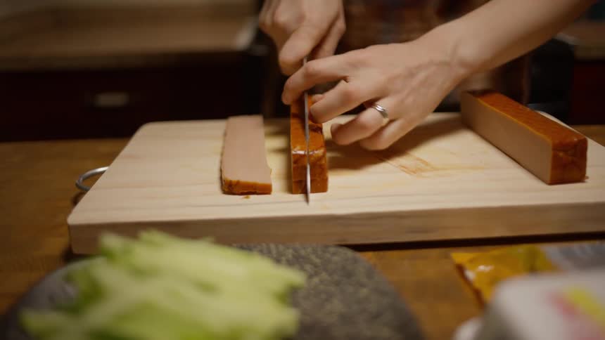 Person cuts meat on a wooden cutting board