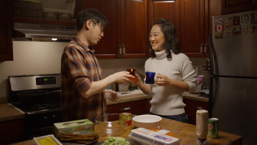 A couple in the kitchen getting ready to cook but before that they have a cup