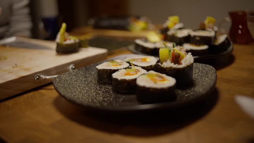 Person arranging sushi in a plate on the counter top