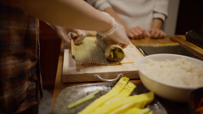 Woman rolling sushi in the kitchen at home