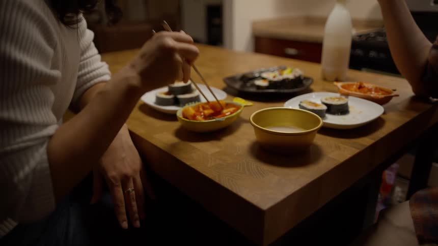 A person picking up food with a utensil on the table and eating it