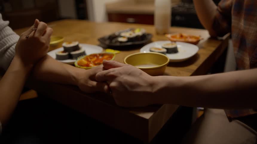A couple holding hands while eating dinner together