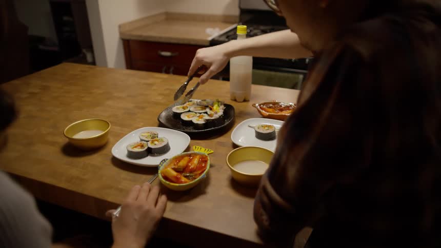 A person serving sushi on another persons plate at the table