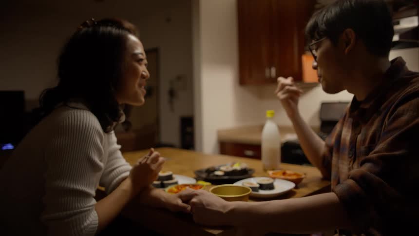 Couple holding hands while eating asian food