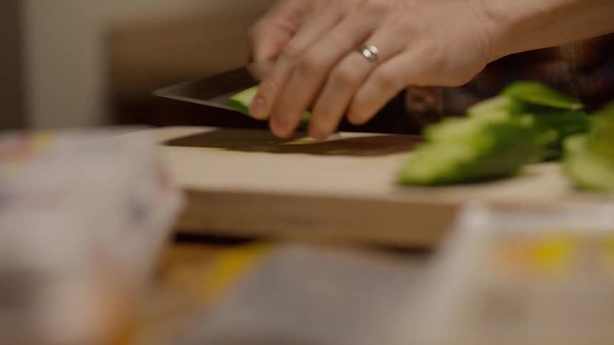 A person carefully slicing a cucumber