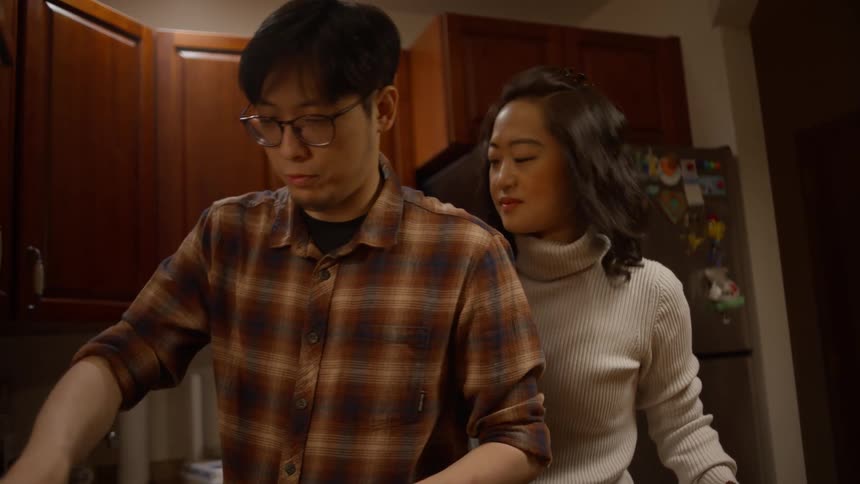 Man cooking with his wife watching from behind